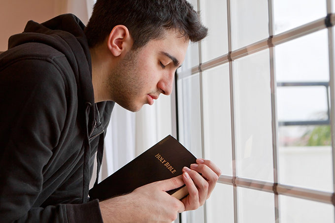 Man Praying While Clutching the Bible