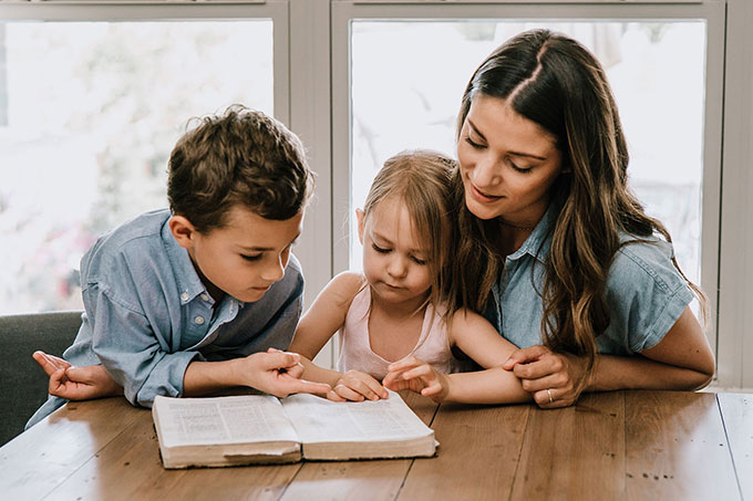 Woman Reading the Bible to Two Child